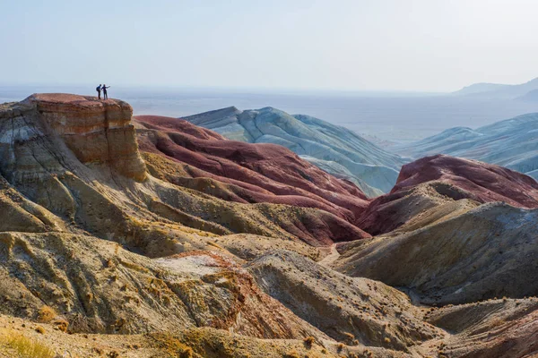 Podróżujący stoją na skraju klifu na tle epickiej góry pustynia krajobraz. — Zdjęcie stockowe