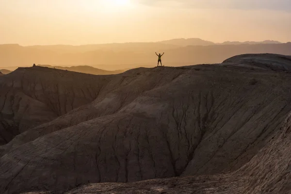 Athlete man stands on top of a hill. The joy of victory. Sunset in the mountains.