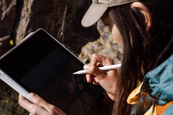 The girl draws the spring landscape of the river on the graphics tablet