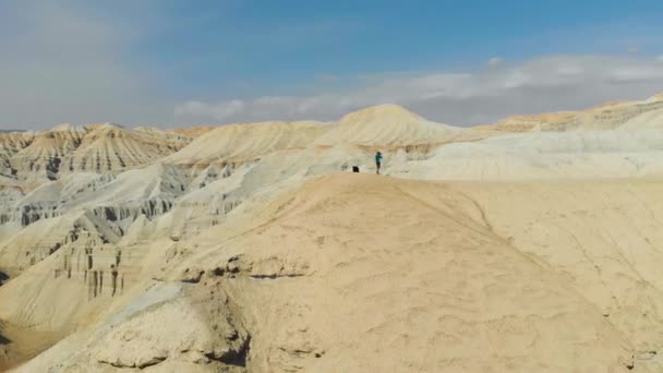 一个男人站在沙漠群山之间的山顶上拍照 沙漠地形 空中视频拍摄 — 图库视频影像