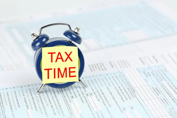 tax concept with yellow note on alarm clock on 1040 form