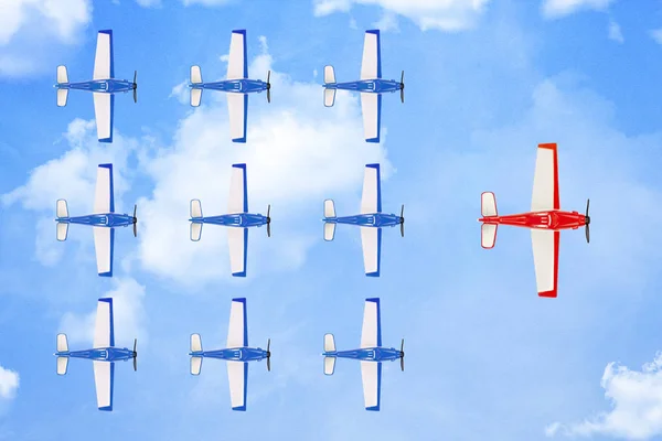 red plane leading a formation of smaller planes on paper surface with clouds, leadership concept