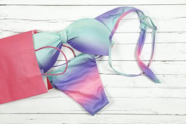 Alış veriş çantasından beyaz tahta üzerine renkli bir bikini.