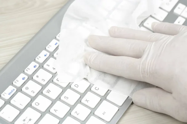 hand in rubber glove cleaning or disinfecting the keyboard
