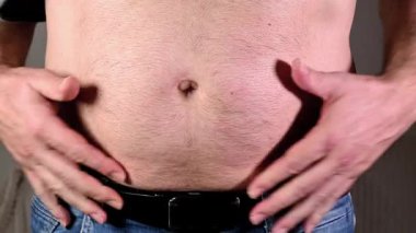 Erkeğin göbek yağlarını kontrol edişine yakın çekim