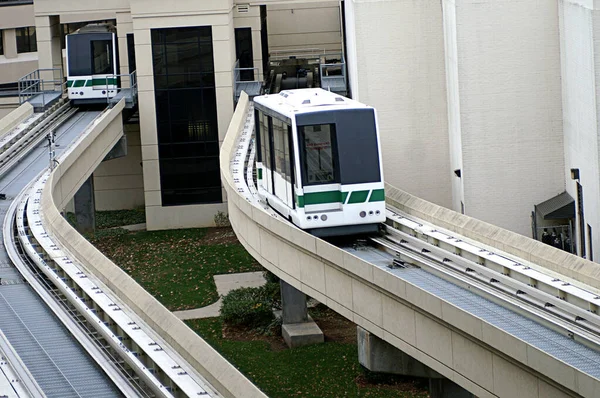 Two rail cars transport passengers between building in busy medical complex