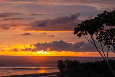 Bulutlar ve gökyüzü canlı renkleri arkasında görülen doğal güzellikleri güzel bir görüntü bırakarak ufuk güneş batmadan farklı bir dağ Uvita, Kosta Rika üst formu