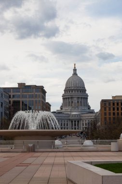 MADISON, WISCONSIN - May 10, 2014:  A water fountain at Monana Terrace with the dome of the capital building in the background in Madison, WI on May 10, 2014. clipart