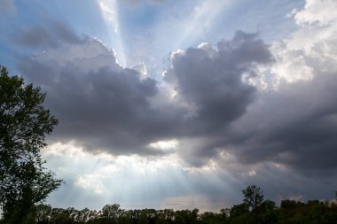 Gökyüzünde bir İncille gözlük kurmaya billowing fırtına bulutları ile güçlü ışık demeti parlaklık.