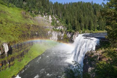 Upper Mesa Şelalesinin sisinde bir gökkuşağı Idaho 'daki Mesa Falls Manzarası boyunca Yılan Nehri' nin Henrys Çatalı 'nın engebeli çölünde bir uçurumdan aşağı yuvarlanırken..