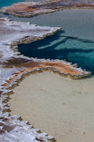 独特の細菌や鉱物の層があるダブレット プールの明るい青い熱水は ワイオミング州イエローストーン国立公園で繊細な縁を作り出しています — ストック写真