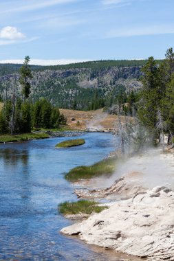 Yellowstone Ulusal Parkı 'ndaki Ateş Deliği Nehri' nin setine güneşli bir yaz gününde Geyser buhar boşaltıyor..