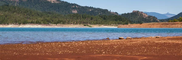 低い水位は カスケード山脈に位置するオレゴン州プロスペクト近くのロスト クリーク湖で赤い粘土と岩を明らかにします — ストック写真