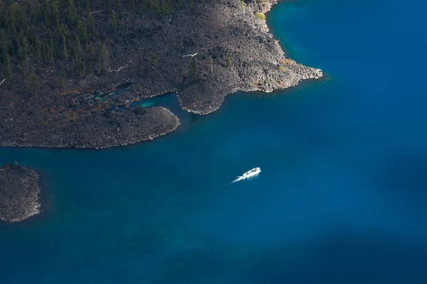 ツアーボートは ウィザード島の端の横にある壮大な青と深いクレーター湖の周りの人々を取ります — ストック写真