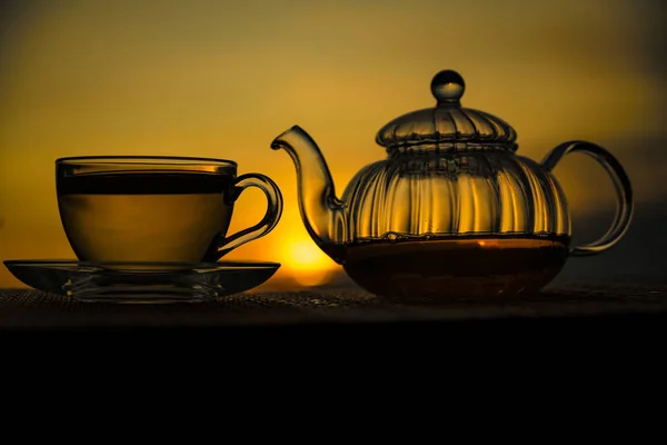 Glass cup and teapot sunset background — Stock Photo, Image