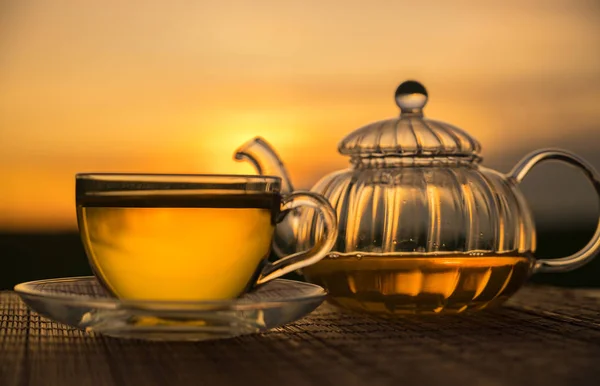 Glass cup and teapot sunset background — Stock Photo, Image