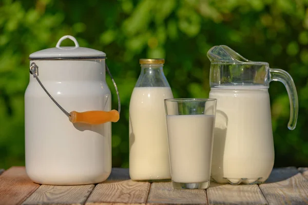 Glas und Krug mit frischer Milch auf Holztisch — Stockfoto