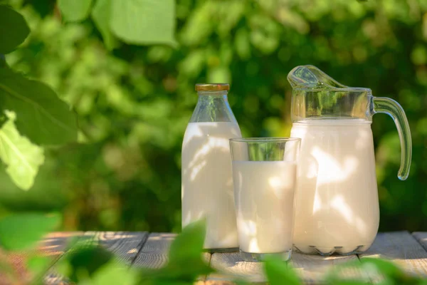 Glas und Krug mit frischer Milch auf Holztisch — Stockfoto