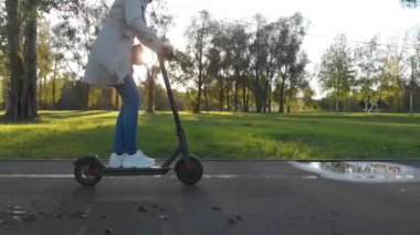 Kız şehir parkında e-scooter kullanıyor.