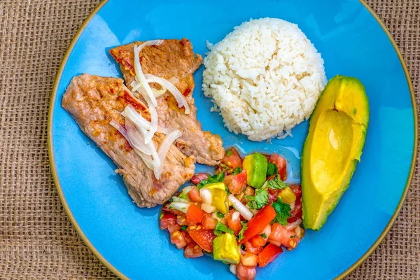 Latin American cuisine fusion: pork steak, white rice,pico de gallo and avocado.Mexican and Cuban cuisine fusion produces a healthy balanced plate of food