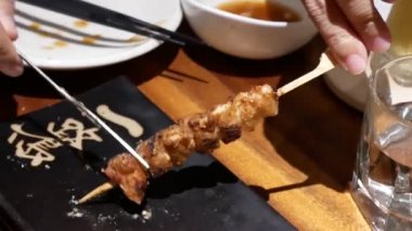 Japon restoranı içinde plaka üzerinde tavuk karaciğer barbekü yemek insanların hareket 