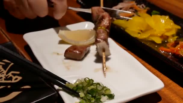 在日本餐厅的盘子里吃鸡乳房烧烤的人的运动 — 图库视频影像