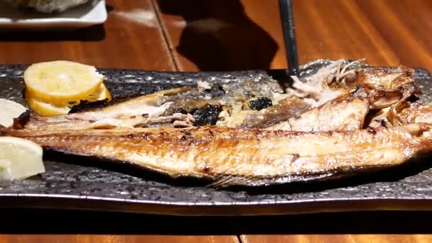 在日本餐厅的餐桌上吃煎鲭鱼和柠檬的人的运动 — 图库视频影像