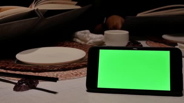 Движение Зеленого Экрана Телефона Размытыми Людьми Смотрящими Меню Внутри Ресторана — стоковое видео
