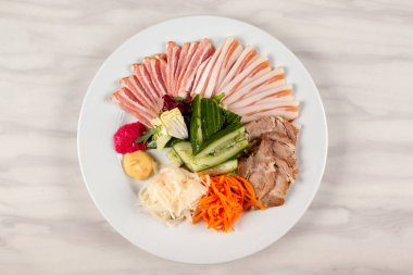 Et ve domuz yağı masanın üzerinde beyaz bir tabakta sebze ile.