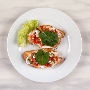 Domates ve beyaz bir plaka üzerinde otlar ile iki sandviç.