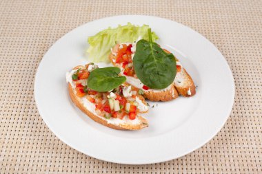 Domates ve beyaz bir plaka üzerinde otlar ile iki sandviç.