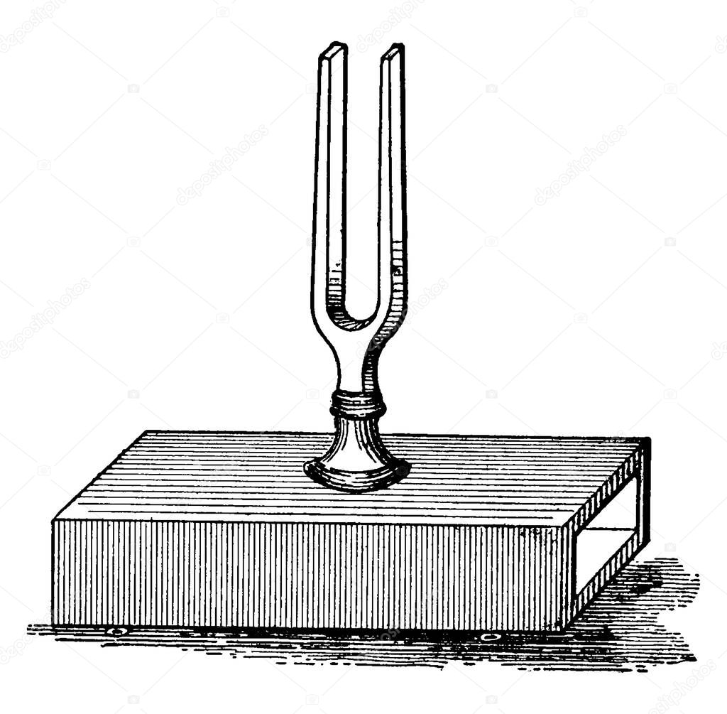 A tuning fork on top of a box, vintage line drawing or engraving illustration.