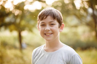 Gülümseyen genç bir çocuk portresi. Doğa, akşam saat, bokeh.