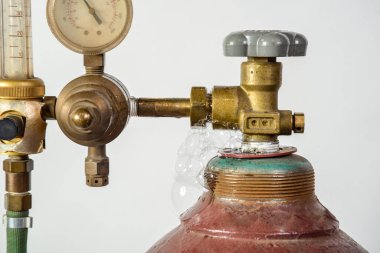 Endüstriyel kaynak için kırmızı gaz silindiri. Çevirmeli, vanalı ve başlıklı.