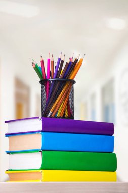 Bir kitap bir tabloda, okul kavramı yığını üzerinde renkli kalemler ile cam