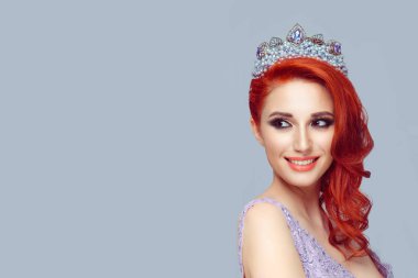 Güzel kızıl saçlı kız morumsu inci taç mor renk arka plan ışık mor duvara geri neşeli seyir kafasına kristal taç ile yan gülümseyen mutlu güzel kadın için seyir izole
