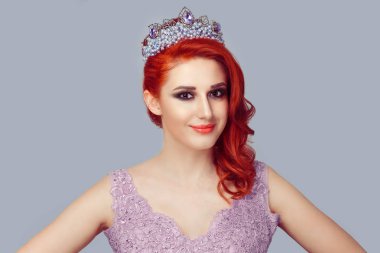 Kendine güvenen güzellik yarışmasında kraliçe. Taç mor inciler ile ciddi Kızıl saçlı kadın ve menekşe rengi dantel kristaller seyir vasıl geçmiş kamera mor dalgalı kıvırcık saçlı bukleler ile vogue tarzı elbise
