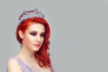 Düşünceli güzel kızıl saçlı kız bir morumsu taç izole açık gri yeşil renk arka plan duvar tarafı hafif gülümseme seyir üzerinde gülümseyen güzel kadın yüz kafasına kristal taç ile inciler