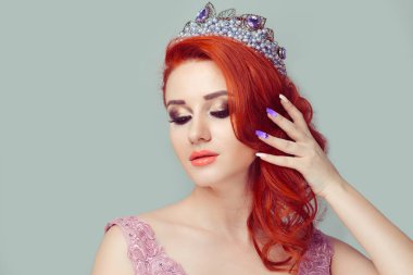 Güzel kız pembemsi bir renkte yan saç hayalifener göz kafasına yeşil arka duvarda izole kristal taç güzel kadınla poz ile saç modeli gösteren dokunmadan aşağı isteyen taç inciler
