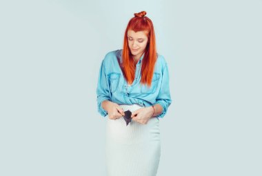 Genç redhead casual kız bebek gelmek ve boş cüzdan mutsuz arıyor olan açık mavi izole bekliyor. Beni parasız bıraktı gebelik kavramı kırdı.