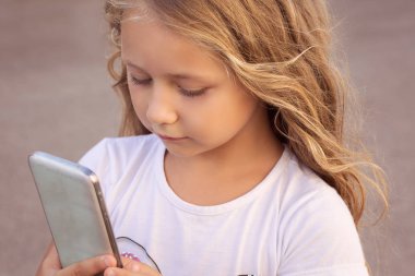 Kız ile konsantrasyon ayakta dışında smartphone kullanarak uzun saçlı içerik