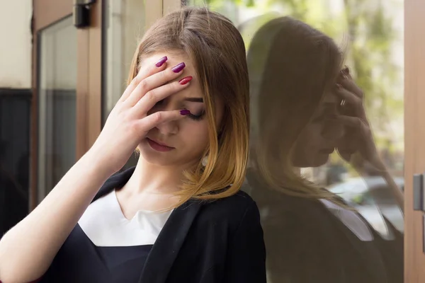 Sad. Closeup portrait stressed upset young woman with hand on face in corporate clothing near office outside. City urban business life style stress