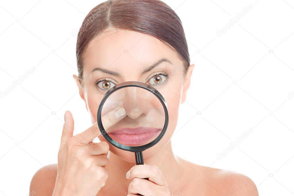 Acne blackheads on woman's nose showed in a magnifying glass, facial scar, skin problem, beauty concept. Girl holding magnifier to show bumpy skin, clog pores, which appears to be clean. Focus on nose