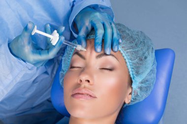 Orta yaş kadın alnında bir klinik cerrahi oda ameliyathane ifade kırışıklıkların kaldırmak için kaşları arasında arka plan Beautify enjeksiyon kaldırma yüz yüz yaşlanma kavramı anti için dolgu veren doktor