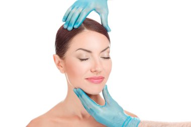 Plastik cerrahi operasyon kozmetik sonra güzel bir kadın. Doktor hasta yüz eller. Portre çekici beyaz kadın esmer beyaz arka plan üzerinde yatay stüdyo çekim izole.