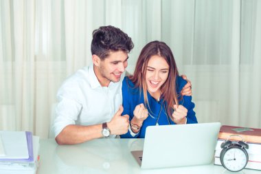 Oturan kadın laptop çalışma ofiste başarı pompalama kutluyor yumruklar ve adam hugs ve destekler onu gösteren başparmak gibi el hareketi.