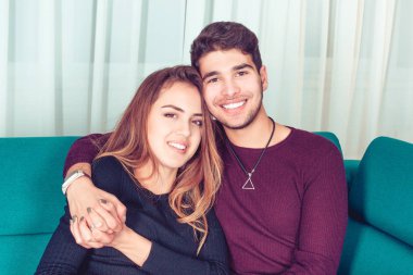 Mutlu çift evde genç gülümseyen portresi dişlek gülümseme beyaz perdeler ile arka plan üzerinde bakıyorsun yeşil mavi koltuk bakimi