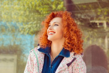 Açık havada bir otobüs durağında gülüyor güzel genç redhead kıvırcık kız portresi. Olumlu insan duyguları, yüz ifadesi, tepki, duyguları.