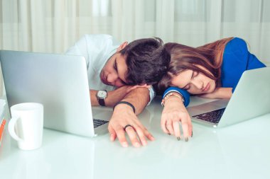 Dizüstü bilgisayarlar ile masanın üzerinde yatan ve tembellik ve oyalanma office uyku uyuyan genç adam ve kadın çift iş arkadaşları. Overworking, geç saatlere kadar gece vardiyası, uykusuz, tembel işçiler kavramı