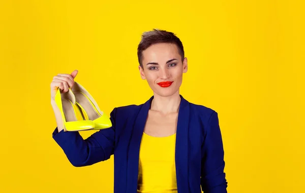 黄色の靴を保持している女性 女性には 概念のかかとが好きです 幸せな笑みを浮かべてハイヒールの つのペアを保持しているを示す黄色の背景の壁に美しいスリムな若い幸せな女性モデル — ストック写真